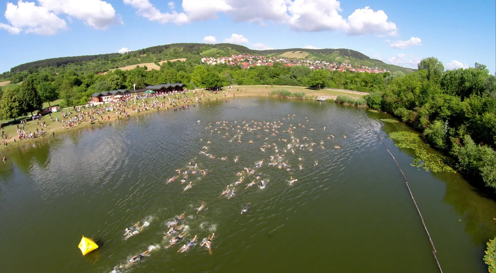 Luftbild vom Erlabrunner See mit Schwimmerinnen und Schwimmern beim Start