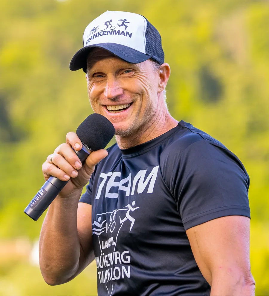 Jürgen Schweighöfer mit Mikrofon im Würzburg-Triathlon-Shirt